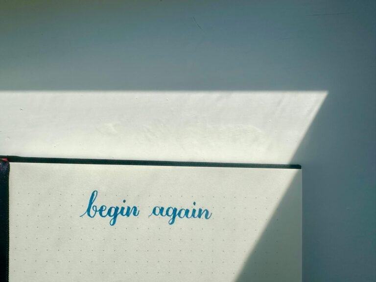 Returning to brush lettering after a break, featuring the words "begin again" written in blue ink.v